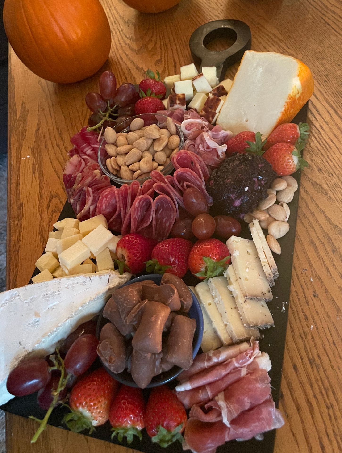 Autumn slate board with cured meats, aged cheeses, strawberries, almonds and chocolates