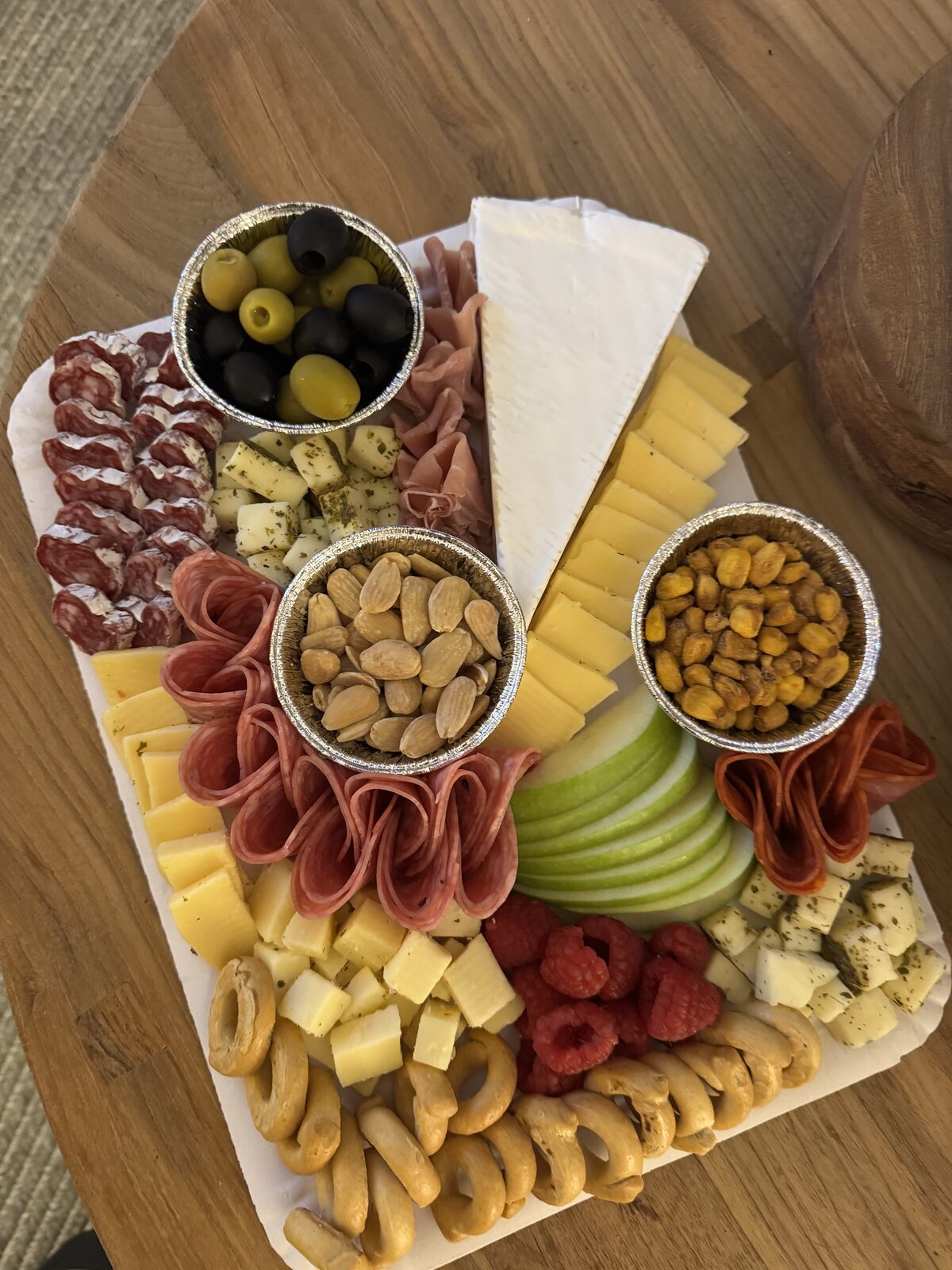 Board with salami roses, brie, marinated cheese, olives, taralli and green apple for a dinner party
