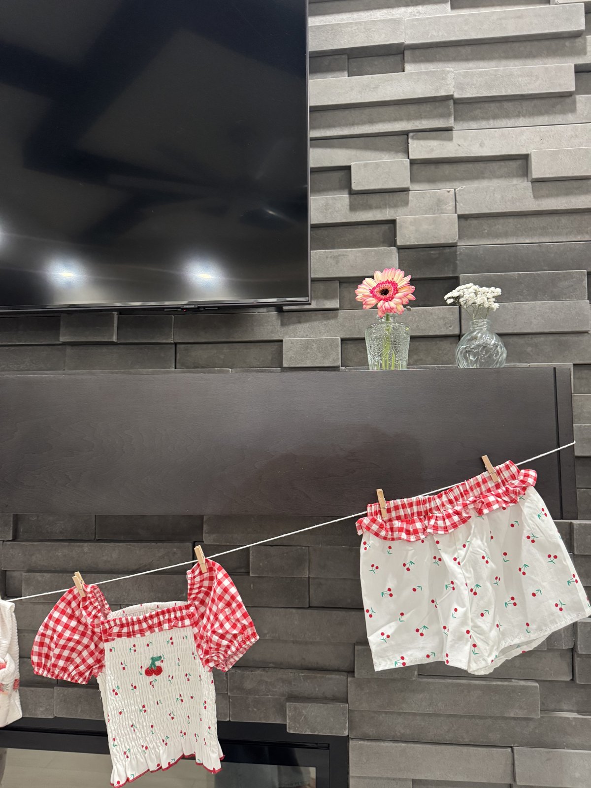 Gingham and cherry baby outfits hung on a clothesline for the shower