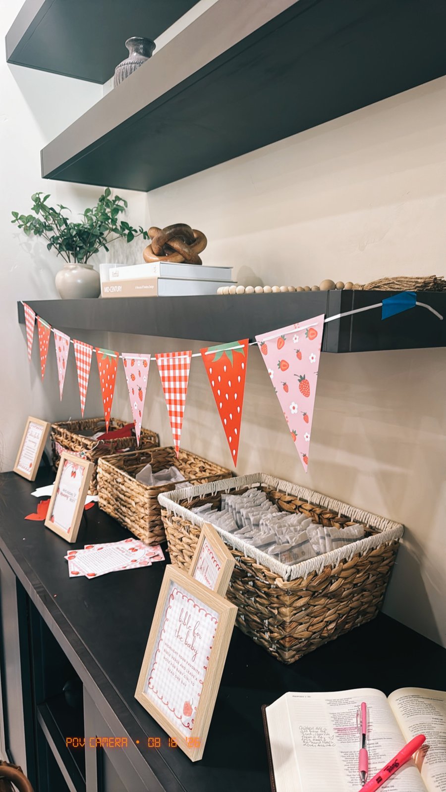 Baby shower game station with strawberry bunting, signage and favour baskets