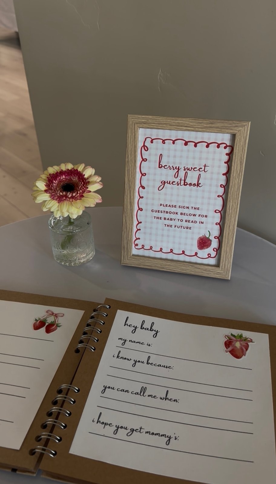The berry sweet guestbook with a framed sign and a gerbera in a glass vase
