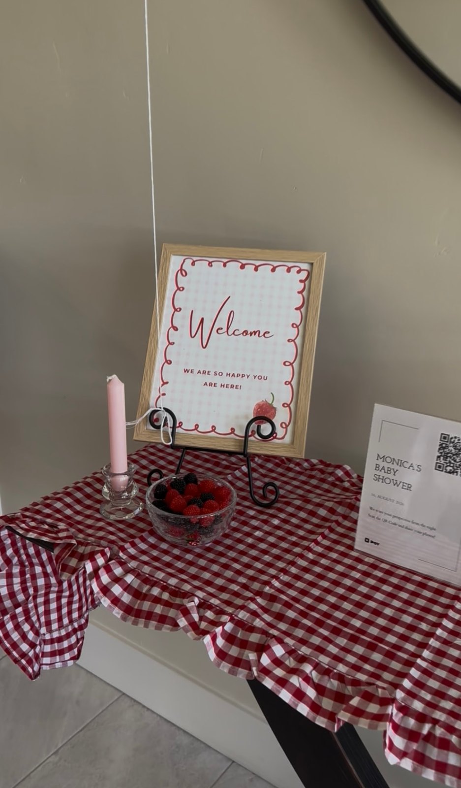 Welcome table with a gingham cloth, framed welcome sign and a bowl of berries