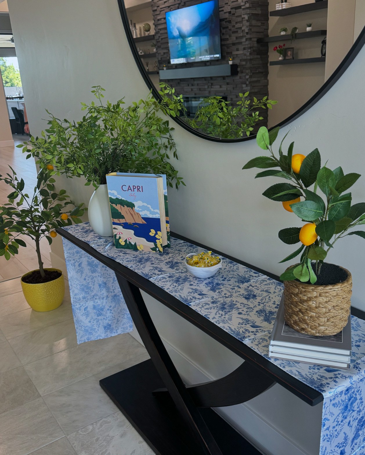 Entry console styled with blue floral linen, lemon trees and a Capri book