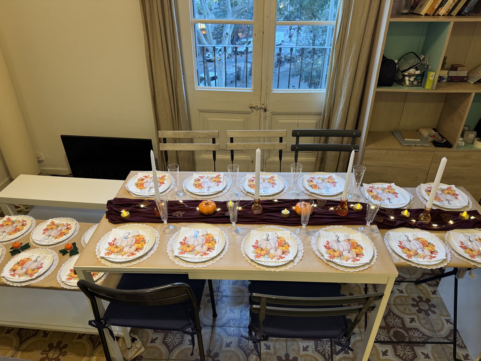 The Thanksgiving table set with pumpkin napkins, lace doilies, taper candles and a burgundy runner